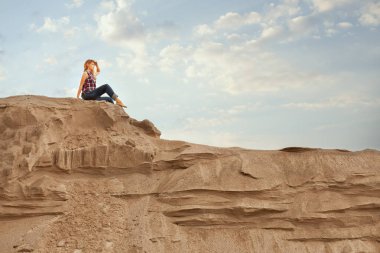Yüksek bir tepe üzerinde ve izlerken kadın oturur.