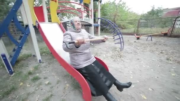 Grandma is riding on a children's hill. — Stock Video