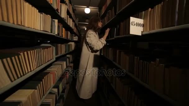 Verschrikkelijke vrouw in de opslagplaats van boeken. — Stockvideo