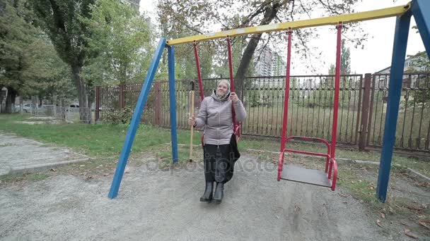 An old grandmother on a child's swing. — Stock Video