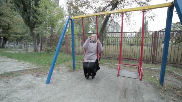 Oude vrouw is swingend op een schommel. — Stockvideo