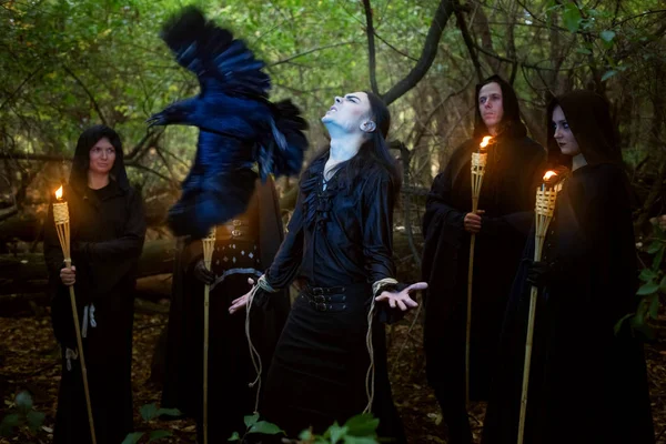 Sorcerers in black cloaks conduct a magical ritual over a man. — 图库照片