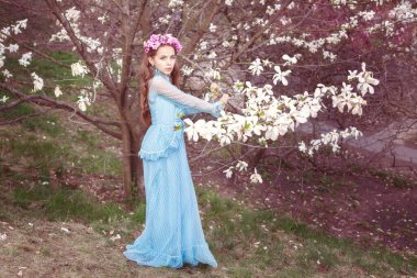 Manolya ağacının yanında tatlı bir kız. Kafasında bir çiçek çelengi var..