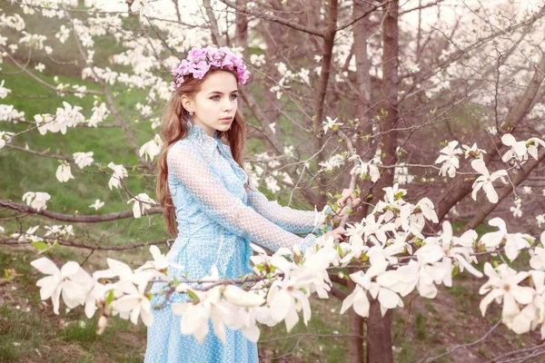 美しい少女はマグノリアの木の近くに立って距離を調べる — ストック写真