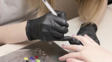 Kadın manikür, tırnaklara bir şekil çizer. Salonda profesyonel manikür..