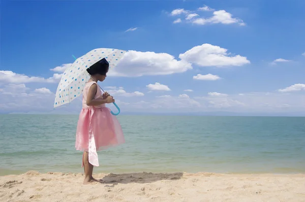 Regenschirm kleines Mädchen stehen auf dem Sand und blauem Himmel — Stockfoto