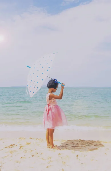 Regenschirm kleines Mädchen stehen auf dem Sand und blauem Himmel — Stockfoto