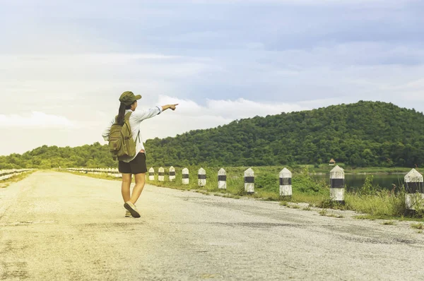 Gezgin kadın el işaret günbatımı tepe üzerinde zevk sırt çantası ile 