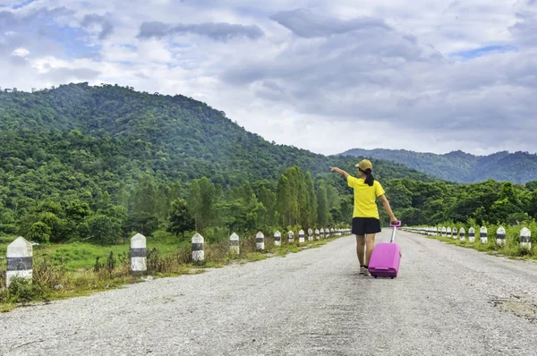 Молодая азиатская женщина с чемоданом ходить в одиночку и горно-голубой — стоковое фото