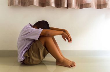 Küçük Asyalı çocuk üzgün ve depresyonda oturma odasında.