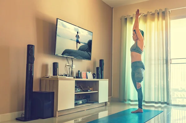 Kadın pratik yoga ve video bilinçlendirilmesini televizyon izlerken bir Telifsiz Stok Fotoğraflar