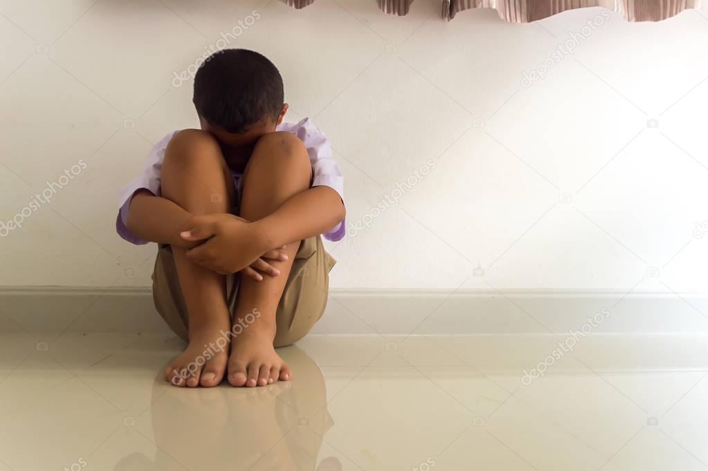 LIttle Asian boy sad and depressed sitting in the room.
