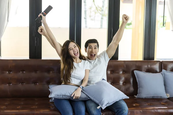Entspannte asiatische junge Paare haben Spaß zu Hause in hell beobachten — Stockfoto