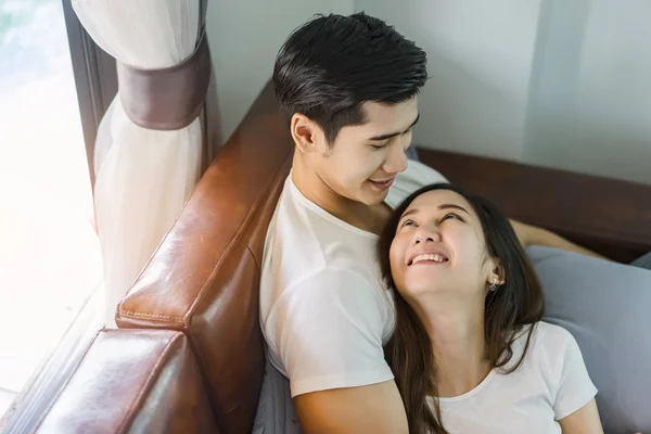 Junges verliebtes Paar sitzt auf einem braunen Sofa. — Stockfoto