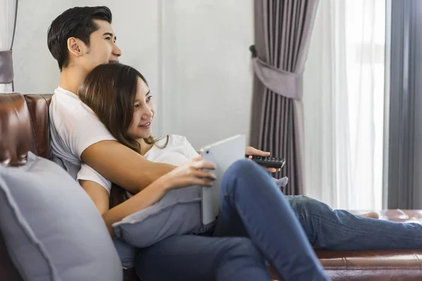 Junges verliebtes Paar sitzt auf einem braunen Sofa und schaut fern — Stockfoto