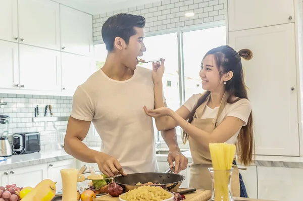 Jonge Aziatische vrouw met spaghetti aan man eten elk voor cooki — Stockfoto