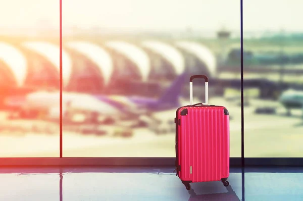 Valize roz în salonul de plecare al aeroportului, avion în backgrou — Fotografie, imagine de stoc