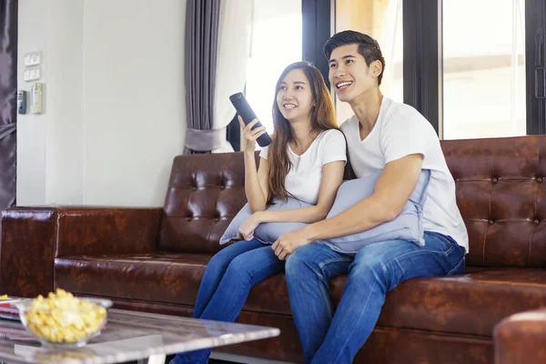 Glücklich asiatische junge Paar auf der Couch beobachten einen Film zusammen. — Stockfoto