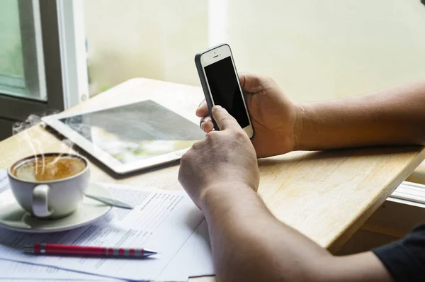 Asiate benutzt Smartphone und trinkt Kaffee. — Stockfoto