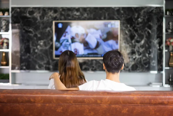 Entspannte asiatische junge Paare vor dem Fernseher zu Hause in hellem Leben Stockbild