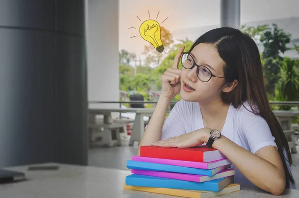 Pensant fille étudiante idée avec des lunettes et des livres sur le bureau, ennuyé Photo De Stock