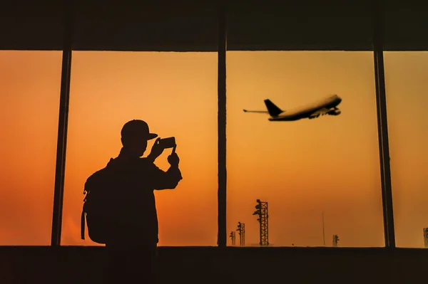 El hombre está de pie cerca de la ventana en el aeropuerto y tomar una foto pl — Foto de Stock