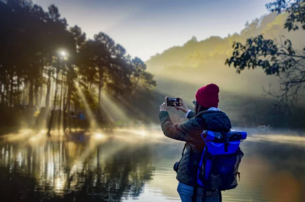 Beautiful woman travel morning sunrise and tourist camping on the lake with foggy in the morning,Pang Ung, Mea Hong Son,North of Thailand.