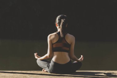 Asya 'lı genç kadın güneş doğarken tahta üzerinde yoga yapıyor..