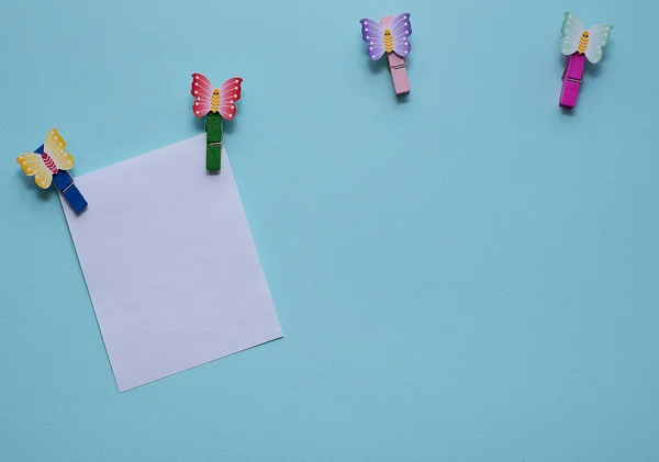 Decoración de diseñador de bodas en forma de marco con anillos, cuentas, un lazo de cinta de satén, rebanada de naranja seca y recortar imágenes. Dos anillos de boda de oro cuelgan de una pinza de madera contra una pared ligera — Foto de Stock