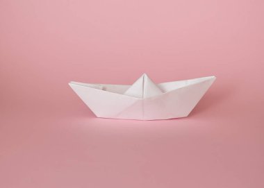 Pembe arka planda eller tarafından yapılan beyaz kağıt tekne.