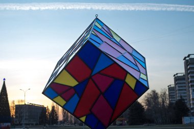 Şehir merkezindeki bir figür, kış akşamında gün batımında çekilen çok renkli bir küpe benziyor.