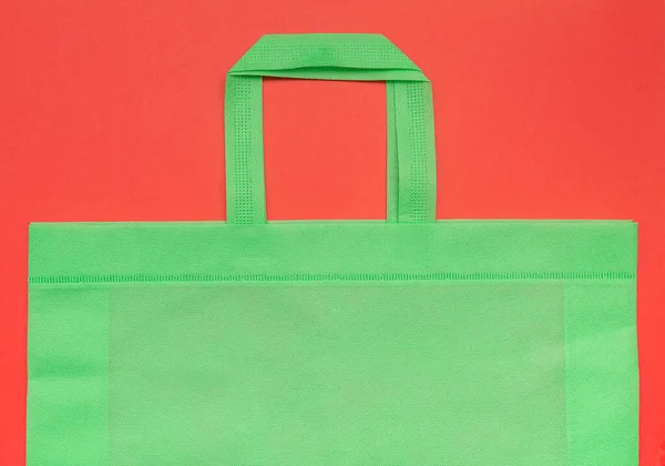 Bolsa natural verde sobre un fondo rojo, producto ecológico, primer plano, para el diseño — Foto de Stock