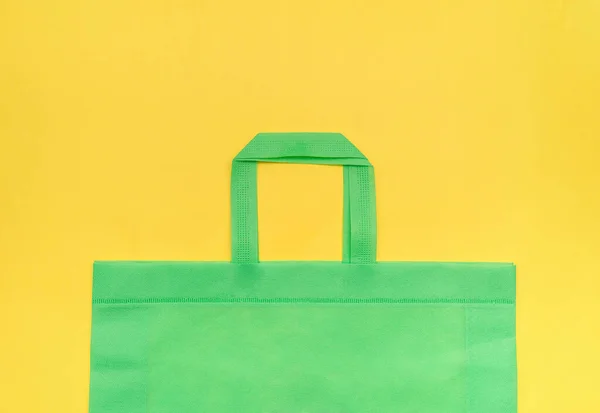 Bolsa natural verde sobre un fondo amarillo, primer plano, para el diseño, lugar para el texto, producto respetuoso del medio ambiente — Foto de Stock