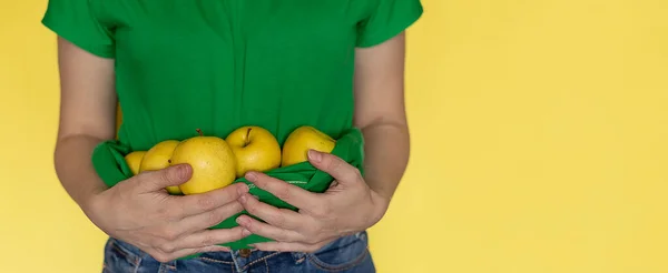 Γυναίκα σε πράσινο t-shirt κρατά μήλο στα χέρια σε κίτρινο φόντο, υγιεινό τρόπο ζωής — Φωτογραφία Αρχείου