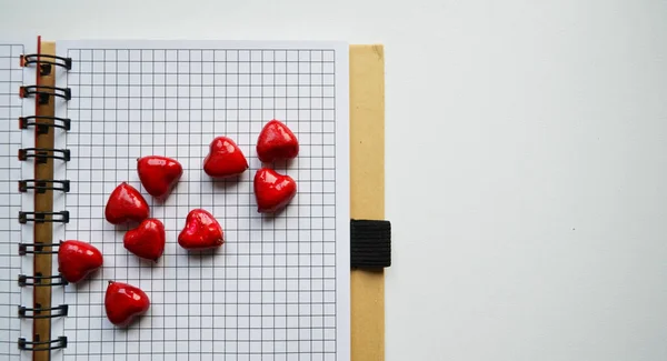 Pequeños corazones rojos con un cuaderno — Foto de Stock
