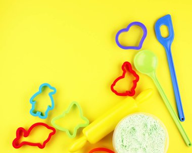 Sarı arka planda Noel zencefilli ekmeği için renkli fırın tavaları. Çocuk oyuncağı kürek, tatil kurabiyesi yapmak için kırmızı penguen..