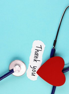 Tıbbi steteskop, kırmızı sağlıklı kalp ve mavi arka planda doktor mesajı. Bir salgın sırasında sağlık çalışanlarına minnettarlık kavramı
