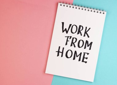 Üzerinde metin olan beyaz bir defter, üst görünüm. Notepad ile pembe ve mavi arkaplan