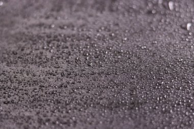 Su damlaları siyah arka planda izole edilmiş. Dağınık damlalı siyah yüzey