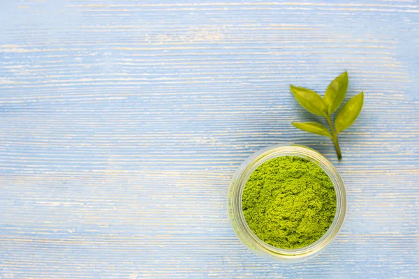 dry green tea powder matcha tea with whole leaves in a white Cup, isolated on a blue background. Chinese healing soothing tea for health. Eastern grass