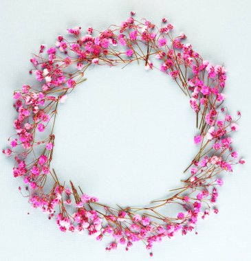 Mavi arkaplan manzaralı mor çiçekler. Çember şeklinde dizilmiş bir sürü bahar çiçeği. Kadınlar için çiçek çelengi