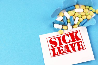 Mesaj, hastalık izni ve mavi arka planda haplar için ödenmiş. Masada dolar ve tıbbi kapsüller var.