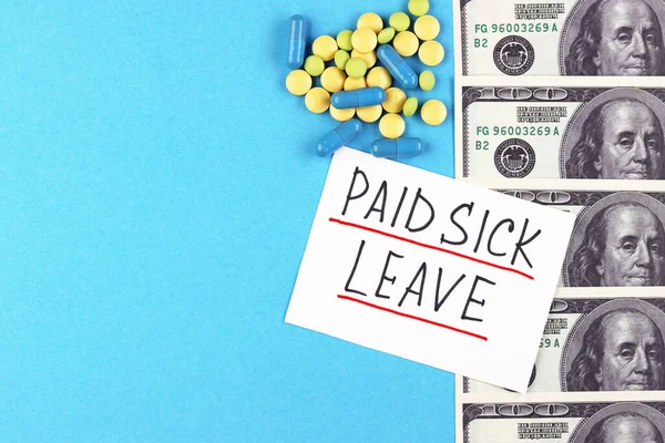 text paid sick leave and money with pills on a blue background. dollars and medical capsules on the table