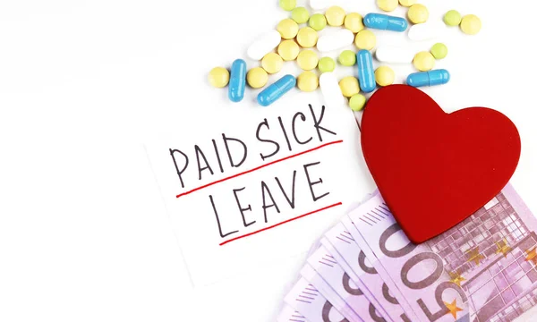 the text of the paid sick leave and money with pills on a white background. red heart and medical capsules on the table