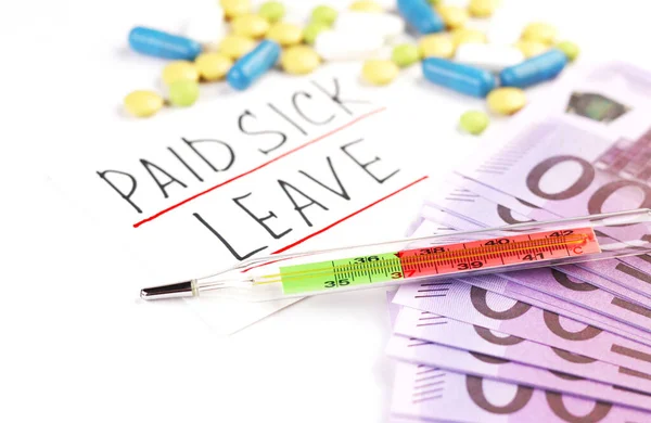 text of paid sick leave and money with pills on a white background. thermometer and medical capsules on the table