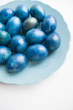 Beyaz arka planda mavi Paskalya yumurtaları, üst manzara. Tatil yumurtaları tabağa konur.