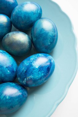 Beyaz arka planda mavi Paskalya yumurtaları, üst manzara. Tatil yumurtaları tabağa konur.