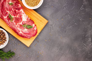 Kesme tahtasında çiğ mermer biftek ve koyu mermer arka planda baharatlar, üst manzara. taze yeşillikler ve sığır eti