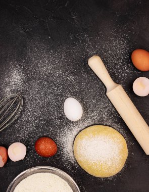 Beyaz un ile kaplı koyu mermer zemin, çırpılmış yumurta, hamur ve oklavayla kaplı. Hamur köftesi pişirme kavramı