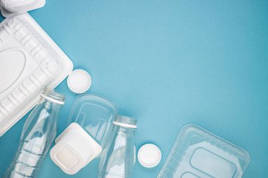 Mavi arka planda şişeleri olan tek kullanımlık plastik sofra takımı. Çevre kirliliğini ve ekolojiyi önlemek için insanları plastik maddeler kullanmamaya teşvik etme kavramı. Plastiğin reddedilmesi.